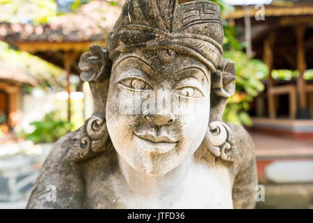 Detail von face-balinesischen Stein Skulptur eines Musikers vor traditionellen Balinesischen geschnitzten Holz Gebäude in den Königlichen Palast, Singaraja, Bali Stockfoto