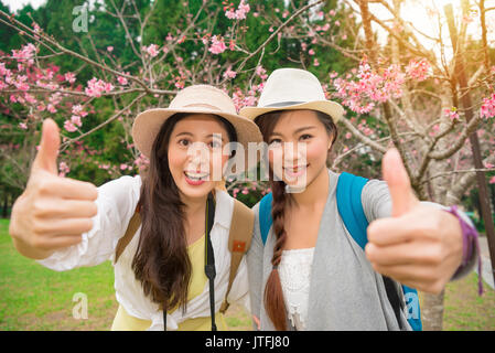 Beste Freunde positive von zwei stilvolle Mädchen Geste die Hände mit Daumen hoch auf Kirsche Blüte Park in Japan. Closeup Portrait von Happy attraktive junge Frauen havi Stockfoto