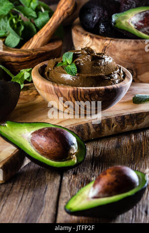 Avocado Mousse au Chocolat in Olivenöl hölzerne Schüssel. Holz- bacground Stockfoto