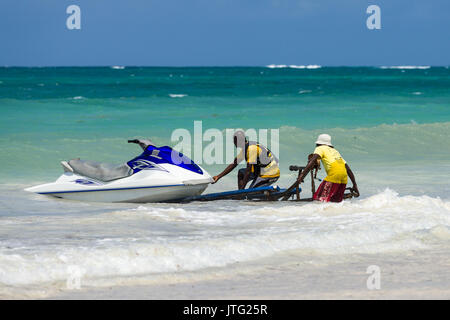 Zwei Männer drücken Jet Ski auf Trailer im Surf, Diani, Kenia Stockfoto