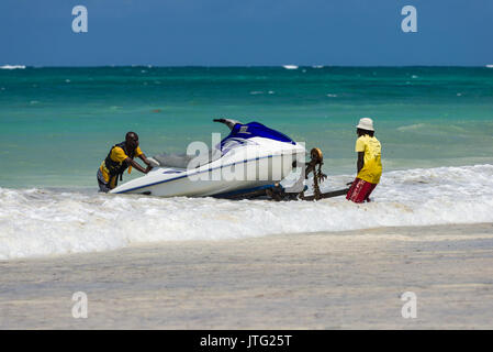 Zwei Männer drücken Jet Ski auf Trailer im Surf, Diani, Kenia Stockfoto