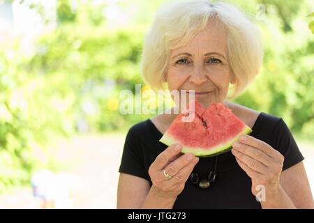 Reife Frau, Essen, Wassermelone. Stockfoto