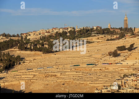 Friedhof und Häuser auf dem Ölberg in Jerusalem, Israel. Tour Busse können am Straßenrand gesehen werden. Stockfoto
