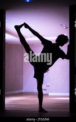 Männliche Yogalehrer tun teilt Bein Strecken Flexibilität Gymnastik und Yoga Asanapraxis im Fitness-Studio Stockfoto