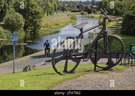 Clydebank, Glasgow, Schottland, Großbritannien. 9. August. Radfahrer auf Ncn 7 Pass die Bankies bike Skulptur an der Clydebank Sommer Wetter gibt und Einheimische genießen Sie den Sommer auf der Forth-and-Clyde-Kanal wie Schottland fängt die Sonne und die britische erleidet unterschiedliche Wetter Credit: Gerard Fähre / alamy Leben Nachrichten Stockfoto