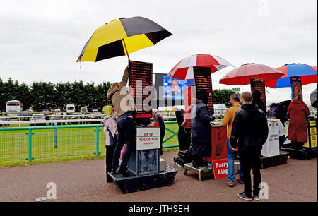 Brighton, UK. 9 Aug, 2017. Ein Buchmacher hat Mühe mit seiner riesigen Schirm am Marstons Renntag in der Maronthonbet Festival der Racing am Brighton Racecourse: Simon Dack/Alamy leben Nachrichten Stockfoto