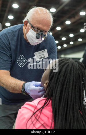 Detroit, Michigan, USA. 9 Aug, 2017. Ein freiwilliger Zahnarzt untersucht die Zähne des Patienten während der Motor City Medical Mission, eine kostenfreie dreitägige medizinische Klinik der Adventist Medical Evangelism Network gesponsert. Quelle: Jim West/Alamy leben Nachrichten Stockfoto