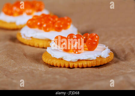 Roter Kaviar in Fisch-form Schüssel mit Cracker, Nahaufnahme, selektiven Fokus Lachskaviar auf Cracker Stockfoto