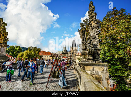 Über die Karlsbrücke in Prag als Künstler ihre Arbeit verkaufen, Touristen genießen Sie den sonnigen Tag und zwei brückentürme sind in der Ferne zu sehen Stockfoto