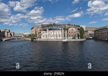 Das schwedische Parlament im Wasser an einem hellen Sommer mit blauem Himmel und weißen Wolken reflektieren. Stockfoto