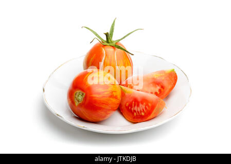 Saftige rote zebra Tomaten in einer kleinen weißen Porzellanteller, auf weißem Hintergrund Stockfoto