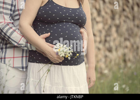 Foto von einem niedlichen schwangeren Bauch mit Wildblumen Stockfoto