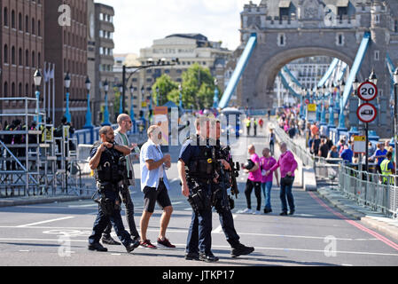 Bewaffnete Polizei, überqueren Sie die Straße in der Nähe der Start der Leichtathletik WM Marathon während der letzten Vorbereitungen getroffen werden. Tower Bridge, London Stockfoto