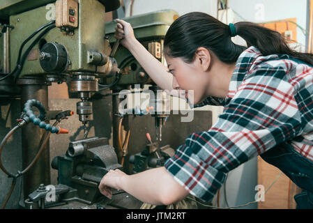 Lächelnde junge Dame Ingenieur in der Fabrik Fräsbearbeitung Abteilung arbeiten und Anpassung der industriellen Maschinen komponenten zu bohren. Stockfoto