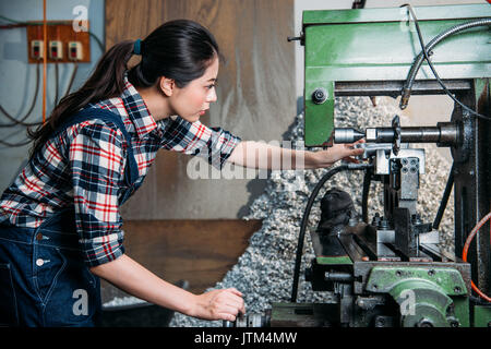 Schöne Komponenten Factory weiblich mit Technologie Maschine bohren und schauen bei der Arbeit im Bereich Fräsen office Personal. Stockfoto