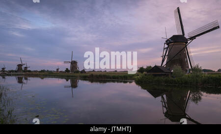 Sonnenuntergang an der malerischen Windmühlen am Wasser entlang in Kinderdijk in den Niederlanden. Stockfoto