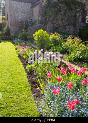 Chenies Manor versunkenen Garten mit Pavillon galerie Mauerwerk. Tulpen hervorgehoben mit Nachmittag Licht. Sonnige anlage Grenzen nach Westen. Hochformat. Stockfoto