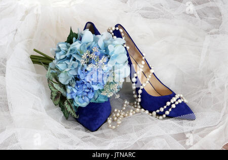 Helle Schuhe für stilvolle Braut. Hell blau wildleder hohen Hügel Paar Schuhe und brides Bouquet mit blauen Blumen auf weißem Bridal Veil. Stockfoto
