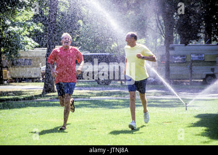 Durch Sprinkler Wasser spielen Arme ausgestreckt liebt das Leben Freiheit aufgeben sorglos Sorglos kindlich verspielter Freude Freude Myrleen Pearson Stockfoto