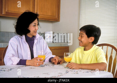 Chinesisch-amerikanische Mutter und Sohn sitzen am Tisch trinken Orangensaft Eltern Kind reden reden reden © Myrleen Pearson Stockfoto