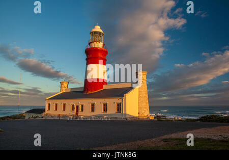 Die historischen des 19. Jahrhunderts Leuchtturm am Cape Agulhas, dem südlichsten Punkt Afrikas, mit seinen markanten roten Turm und Sandstein ende Türme bei Sonnenuntergang Stockfoto