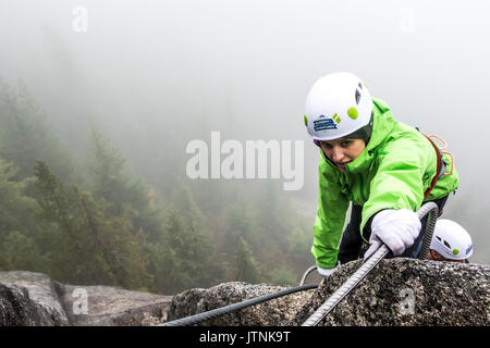 Eine Frauen hat für die Metall- rung beim Klettern Klettersteig in Squamish, British Columbia. Stockfoto