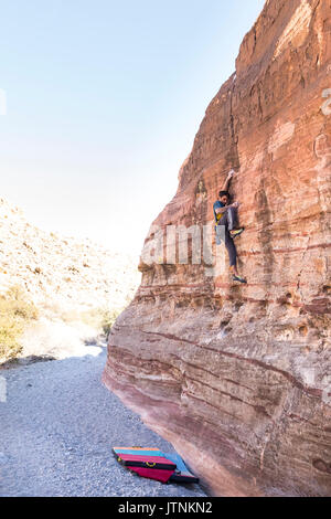 Ein Mann steigt auf einem hohen Wand allein in Red Rocks National Park, Nevada Stockfoto