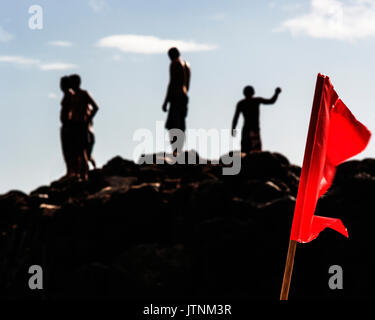 Silhouette einer Gruppe junger Männer auf einem Felsen in der Waimea Bay Beach Park, O'ahu, Hawaii, USA stehend Stockfoto