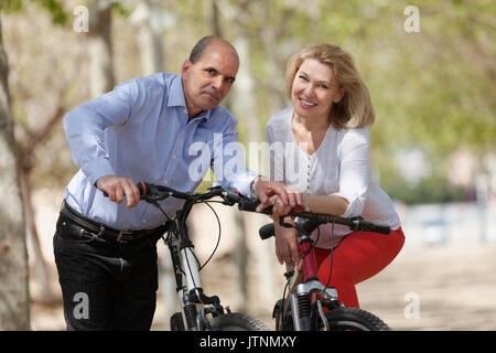 Lächelnd internationale Familie der aktiven Rentner mit Bikes im sonnigen Tag Stockfoto