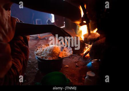 Ester Hodari, Alter 22 Jahre alt, kocht das Abendessen mit dem traditionellen 3-rock Koch Herd mit einem Feuer in der Mitte. Diese cookstoves verwenden eine Menge Kraftstoff, Brennholz, und viel Rauch erzeugen. Ester sagte uns, dass das Kochen mit dieser Art von Herd ihre Augen sind rot und Sie mussten oft eine Brust Husten. Ihre Kinder im Alter von 5, 2 und 3 Monaten werden oft mit ihr, als sie kocht. Ihre Schwägerin, shadya Dienstag, Alter 11, hilft ihr Kochen. Vor nicht allzu langer Zeit Esterâs 3 Monate alten einen Husten entwickelt, es wurde immer schlimmer und so nahmen sie Stockfoto