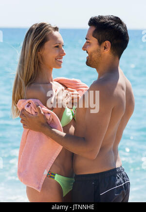 Portrait von Glückliche erwachsene Paare im Handtuch auf Sandstrand gewickelt Stockfoto