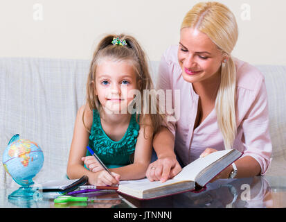 Portrait von lächelnden jungen blonden Frau und kleines Mädchen in Lektion im Innenbereich Stockfoto