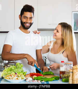 Junge interracial Paare Kochen Gemüse und Lachen Stockfoto