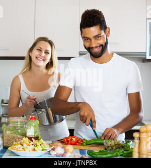 Lächelnden jungen interracial Paare Kochen Gemüse und lachend in der Küche Stockfoto