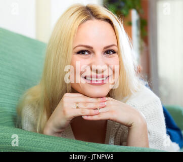 Junge attraktive Frau lächelt charmant liying auf einem Sofa im Innenbereich Stockfoto