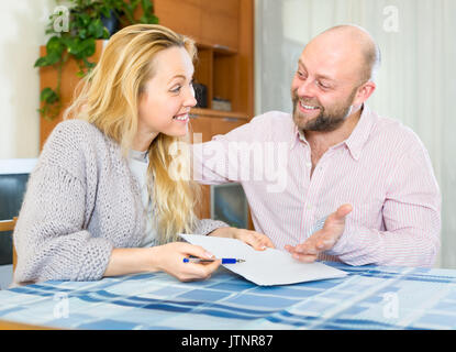 Happy positive lächelnde Paar an jedem anderen Suchen und Halten der Papiere in ihren Händen Stockfoto