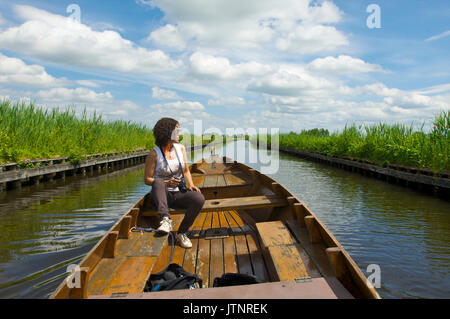 Frau in ein hölzernes Boot in einem Kanal mit einem Foto Kamera die Natur genießen in der Nähe von Giethoorn, Niederlande Stockfoto