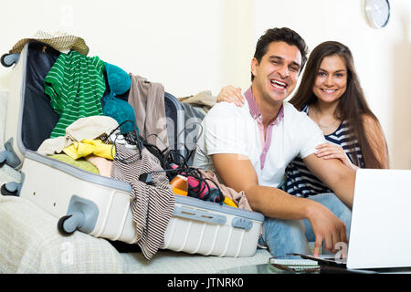 Attraktive junge Eheleute im Web surfen und Verpackung Gepäck zu Hause Stockfoto