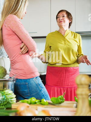 Traurig reife Frau mit erwachsener Tochter teilen schlechte Nachrichten in der Küche zu Hause. Stockfoto