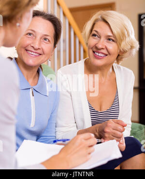 Lächelnd älterer Frauen, die Beratung bei der Versicherung zu Hause. Konzentrieren Sie sich auf die richtige Frau Stockfoto