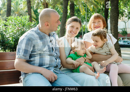 Happy multigeneration Familie von fünf sitzt auf der Bank im sonnigen Sommertag Stockfoto