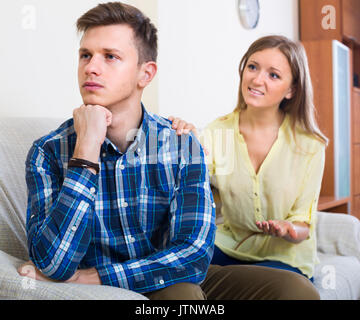 Junge Frau versucht es mit beleidigte Partner zu Hause Stockfoto