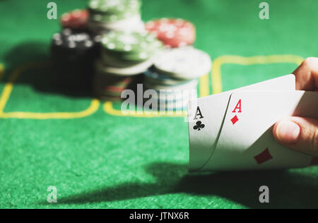 Casino Konzept. Zwei Asse in der Hand. Grün Pokertisch und Spieljetons Stockfoto