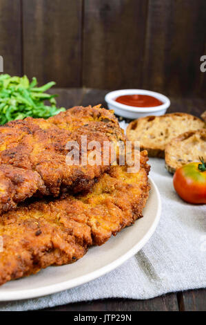 Eine große Wiener Schnitzel auf einem dunklen Hintergrund. Vertikale Ansicht Stockfoto