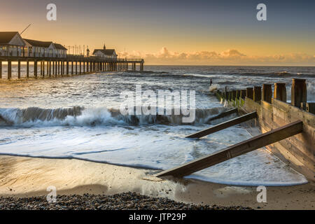 Die Sonne geht hinter dem Pier in der beliebten Suffolk Seebad Southwold an einem stürmischen morgen Anfang August. Stockfoto