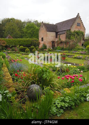 Porträt Blick auf den Pavillon Galerie an chenies Manor versunkenen Garten im Frühling, bunte Tulpen, Auswahl an frischem grünem Laub und Zierteich. Stockfoto