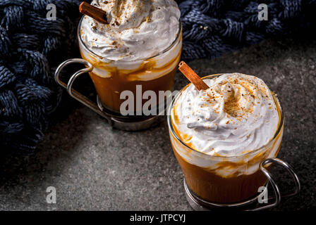 Traditionelle herbst Gerichte. Halloween, Thanksgiving. Heiß und würzig aromatischen Kürbis Latte mit Zimt auf Schwarzen Tisch aus Stein, mit Decke. Platz kopieren Stockfoto