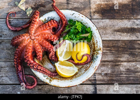 Big gekochten Tintenfisch mit Zitrone und Petersilie, rustikaler Stil, Ansicht von oben Stockfoto