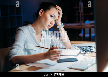 Junge müde asiatischen Geschäftsfrau in weißer Bluse arbeiten bis spät im Büro Stockfoto