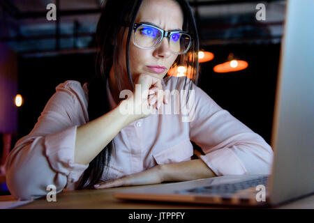 Junge nachdenklich kaukasischen Geschäftsfrau in Gläsern auf Laptop suchen Stockfoto